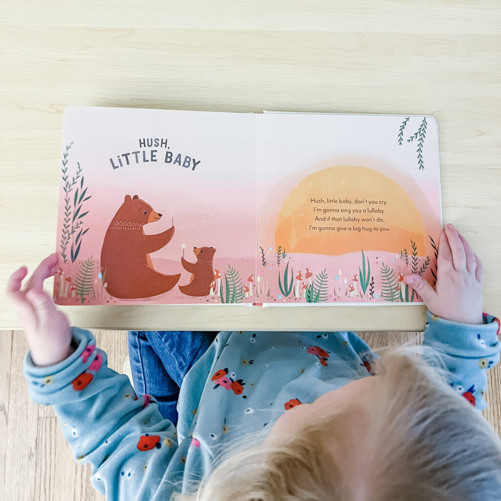 Child looking at open board book with picture of brown bear and bear cub