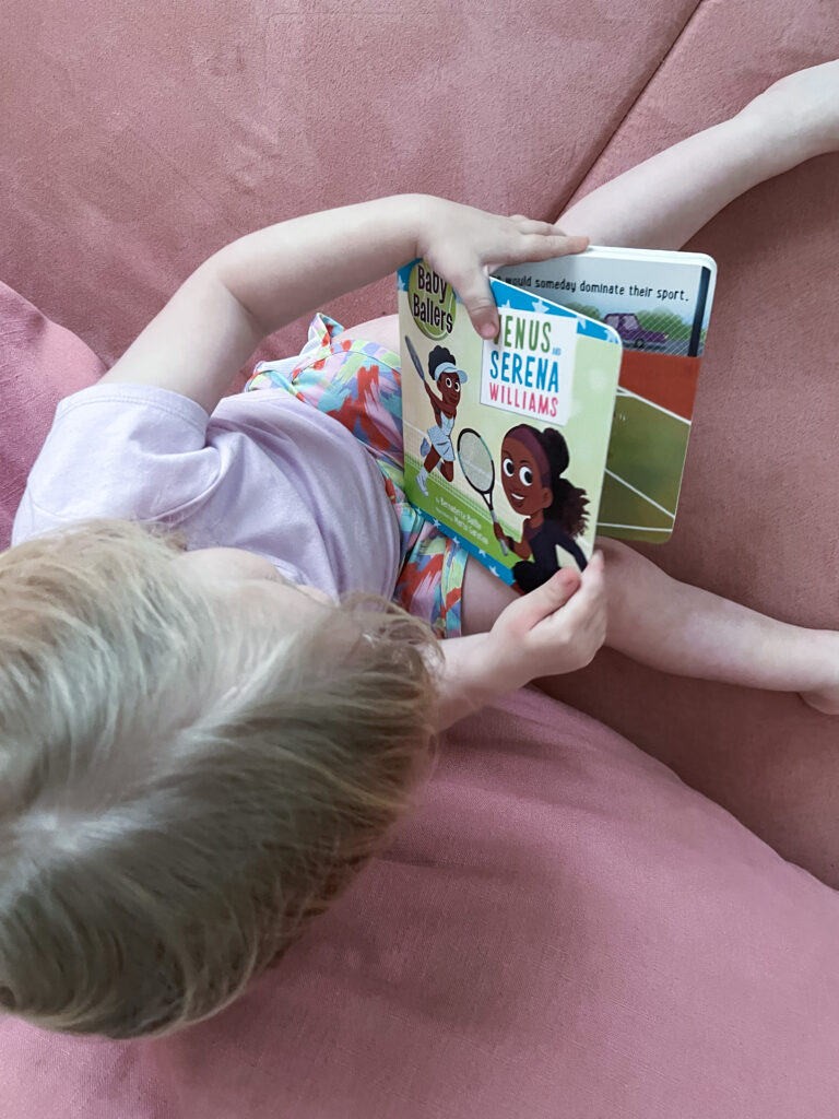 Child holding board book Baby Ballers: Venus and Serena Williams