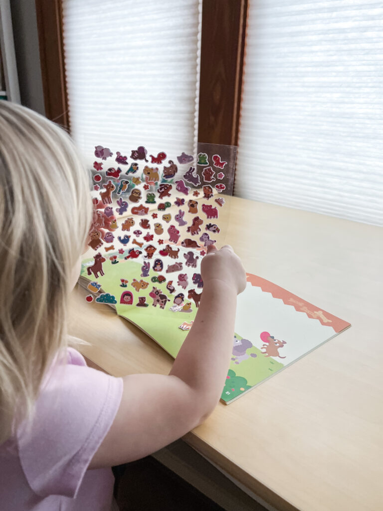 Child holding sheet of stickers from activity book Super Puffy Stickers! Baby Animals