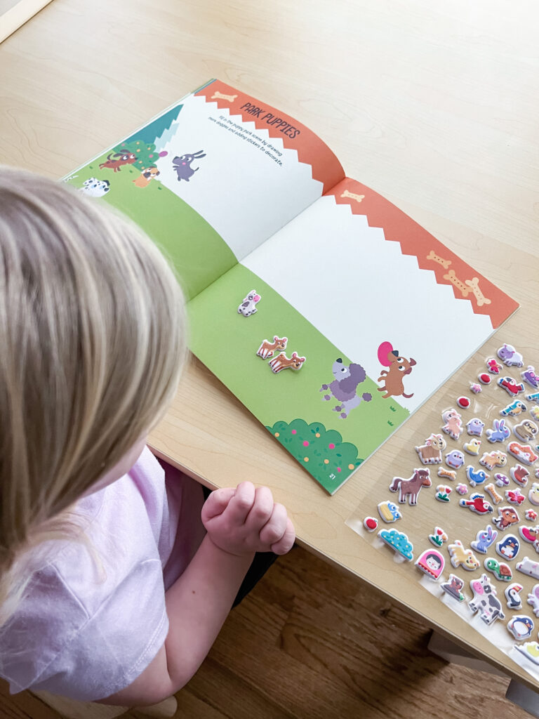 Child looking at sticker pages from activity book Super Puffy Stickers! Baby Animals